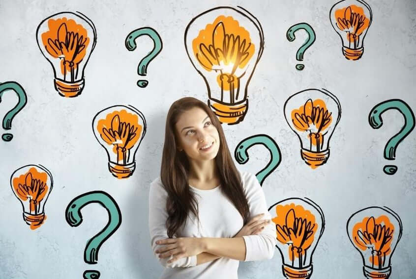 Woman stood in front of a screen which shows question marks and lightbulbs. Image indicates the woman is asking questions about her coffee including how to store it and keep it fresh. Woman is smiling as ger queries have been answered.
